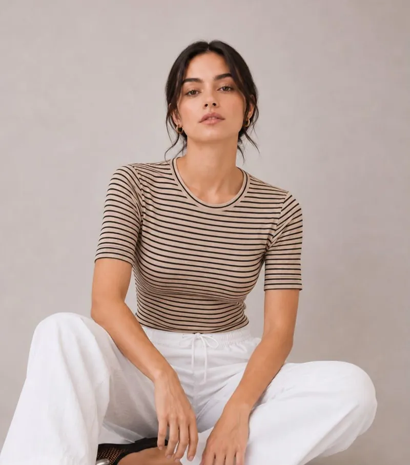 Mujer sentada con camiseta de rayas beige y negro y pantalón blanco amplio